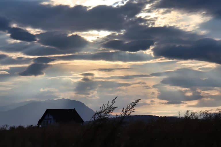 Building in a field in Romania during sunset, silhouette of building and plants are shown.